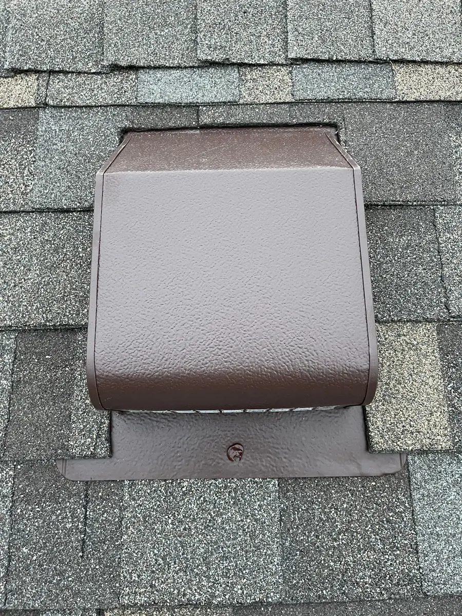 New brown metal box vent nailed over shingles on a roof slope