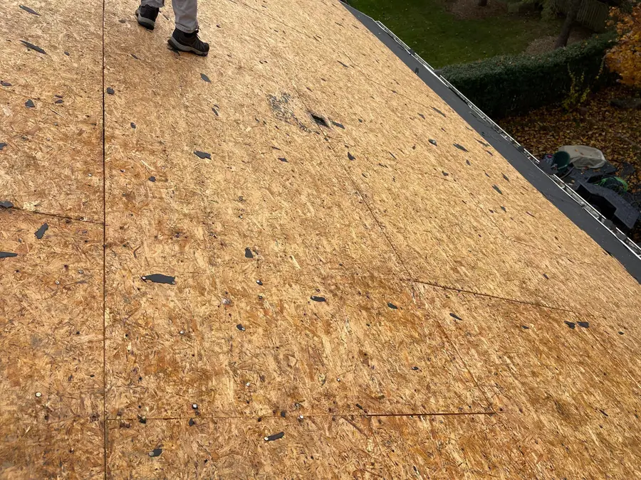 Bare OSB roof deck after tear-off with scraps of old felt and nail holes
